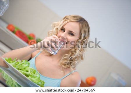 young woman in kitchen eating salad in kitchen
