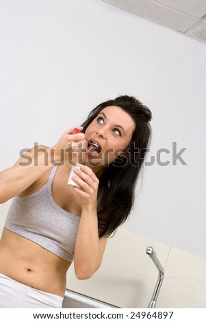 young caucasian brunette woman eating yogurt in a kitchen,with gym wear.Concept of healthy lifestyle trough a correct food.