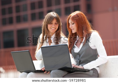 two young adult caucasian businesswoman,working outdoors with two laptop