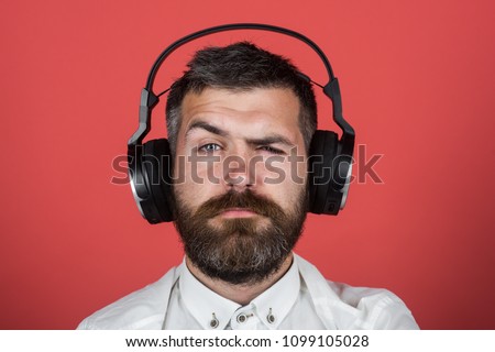 Music, enjoyment, leisure, technology, style, lifestyle and people concept - stylish serious man listening to music. Bearded hipster listening music in earphones. Man listens to music using headphones
