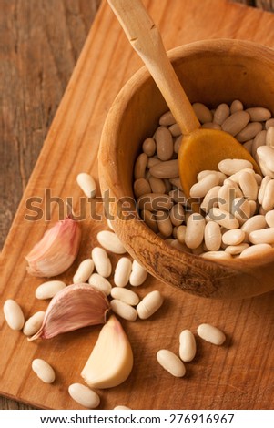 Beans in a wood pot on natural textured wood background. Natural uncooked raw organic food