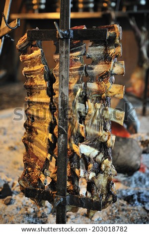 Asado, traditional barbecue dish in Argentina, roasted meat of beef cooked on a vertical grills placed around fire