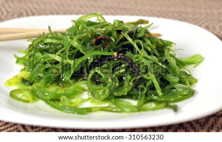chuka salad of green seaweed with sesame seeds on a bamboo napkin with bamboo sticks