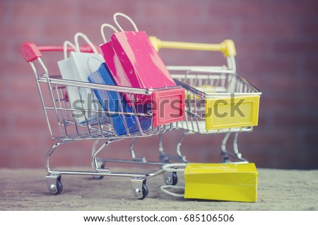 Paper shopping bags  in a shopping cart on wood table,e-commerce or electronic commerce is a transaction of buying or selling goods or services online over the internet.