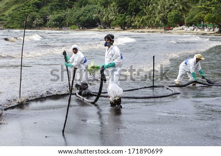 RAYONG, THAILAND - JULY 31, 2013: Workers remove crude oil from the Ao Proa beach,  Koh Samet Island, Rayong province, Thailand.
