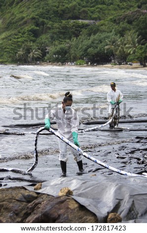 RAYONG, THAILAND - JULY 31, 2013: Workers remove crude oil from the Ao Proa beach, Koh Samet Island, Rayong province, Thailand.