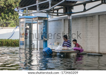 Bangkok - Thailand, Nov 6, 2011: A woman and her son selling a food at the bus stop At Soi Chinnakhet, Ngamwongwan road during a big flooding in Thailand.