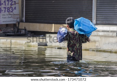 Bangkok - Thailand, Nov 6, 2011: A man carrying a big bag walking along Ngamwongwan road during a big flooding in Thailand.