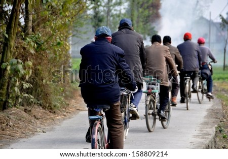 PENGZHOU, CHINA:  A group of men riding their bicycles along a country road