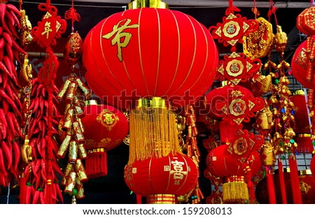 PENGZHOU, CHINA:  Beautiful red fabric lanterns, strings of Chili peppers, and other decorations sold for the Chinese New Year hang in front of a local shop