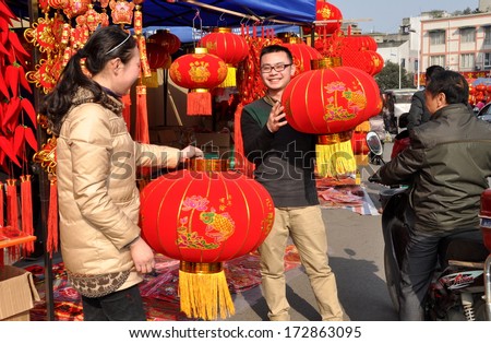 Pengzhou, China January 22, 2014: Man and woman holding large red lanterns at their stall where they sell items for the Chinese Lunar New Year