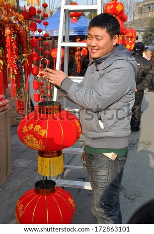 Pengzhou, China January 22, 2014:  Man holding double lanterns contemplates buying them for Chinese New Year decorations
