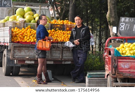 Pengzhou, China October 26, 2013:  Man selling oranges and pomelo fruits from his truck parked along a city highway
