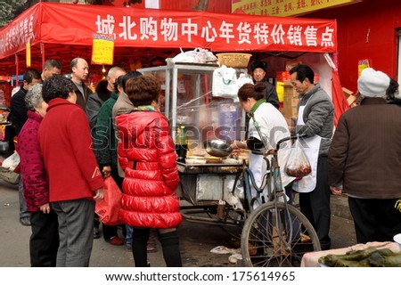 Pengzhou, China January 29, 2014:  People lining up to buy specialty foods for the Chinese New Year holiday at a street vendor\'s stand