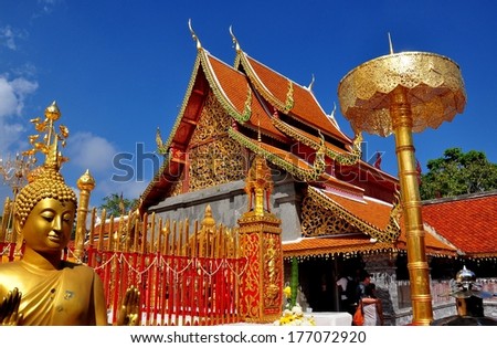 Chiang Mai, Thailand - December 27, 2012: Lord Buddha (left), the opulent Vihara (center) and a large metal, gilded parasol on the upper terrace at Wat Doi Suthep