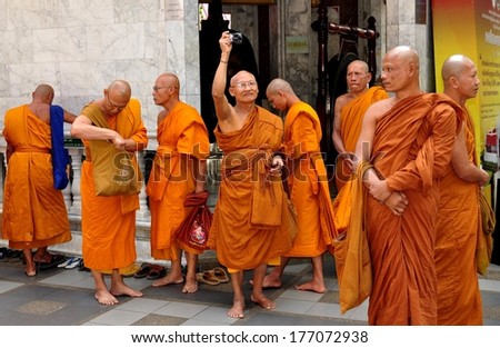 Chiang Mai, Thailand - December 27, 2012::  A group of monks wearing orange and sienna coloured robes gathered on the lower terrace at Wat Doi Suthep