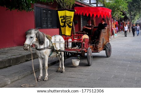 Langzhong Ancient City, China - October 22, 2013:  Horse-drawn old-style wooden carriage with its drivers waiting for fares on Wumiao (West) Street