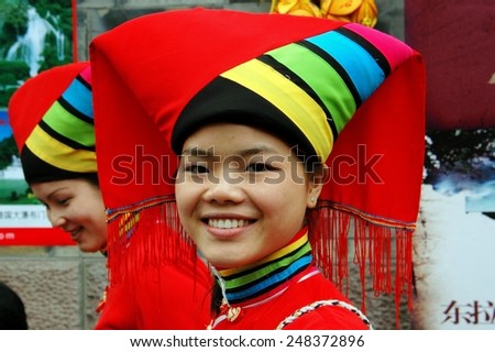 Chengdu, China - April 12, 2006:  Smiling Chinese woman wearing traditional Yi People clothing  with large headdress on historic Jin Li Street