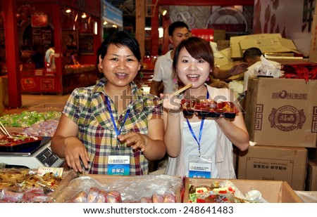Chengdu, China - September 15, 2010:  Smiling women selling moon cakes while eating lunch at the 10th Chinese Moon Cake Festival at the annual Sichuan and Tianfu Food Fair