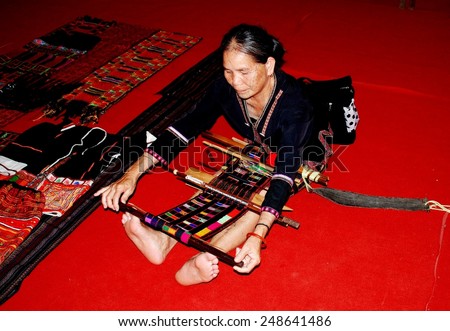 Chengdu, China - May 27, 2007:  Crafts woman seated on red carpet making clothing with a traditional hand loom in Hainan Hall at the International Festival of Intangible Cultural Heritage Exposition