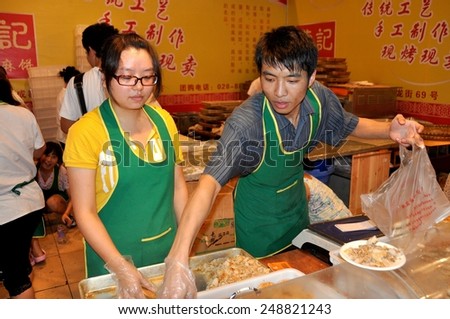 Chengdu, China - September 15, 2010:  Two workers selling food at the 10th Chinese Moon Cake Festival at the annual Sichuan and Tianfu Food Fair