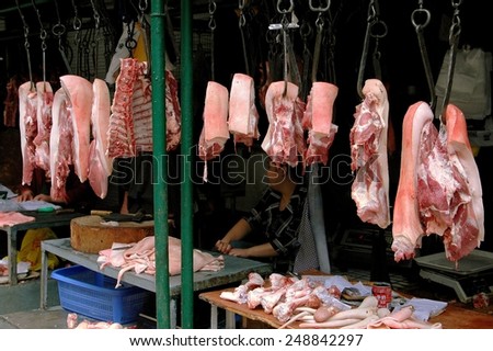 Chengdu, China - September 18, 2006:  Qing Shi Qiao marketplace butcher\'s stall with slabs of meat hanging from iron hooks and chickens displayed on tables