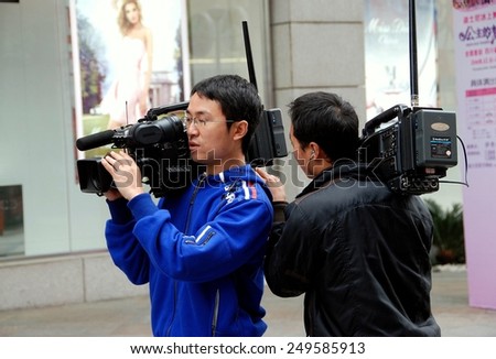 Chengdu, China - November 14, 2007:  TV news crew with video cameras preparing to interview passerby on Chun Xi Street