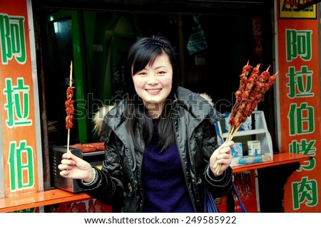 Chengdu, China - January 21, 2008: Smiling young Chinese woman holding barbecued meat on wooden sticks at her food stall on Chunjie Road