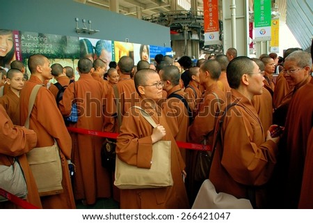 Hong Kong, China - December 12, 2006:  A contingent of Buddhist monks in orange robes carrying large shoulder bags queues to board the Ngong Ping Skyrail cable car ride to Lantau Island