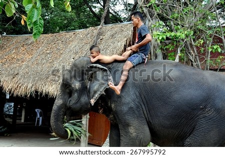 Ayutthaya, Thailand - December 22, 2010:  Thai father with his naked toddler son riding atop an elephant at the Ayutthaya Elephant Royal Palace & Kraal