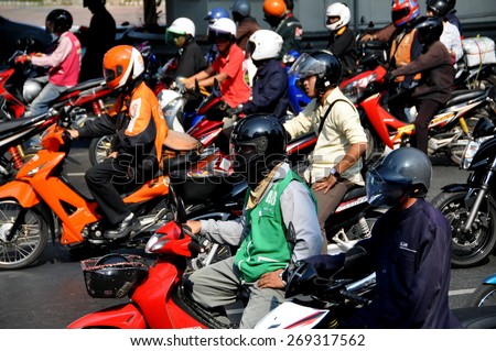Bangkok, Thailand - December 23, 2009:  People wearing mandatory helmets seated on their motorbikes waiting patiently at a traffic light on Silom Road