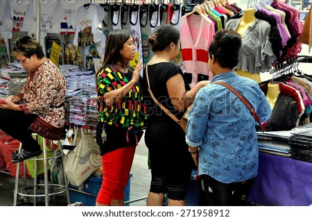 Bangkok, Thailand - December 23, 2013:  Three Thai women shopping for bargain clothing at an outdoor street market on Thanon Ratchaprasong