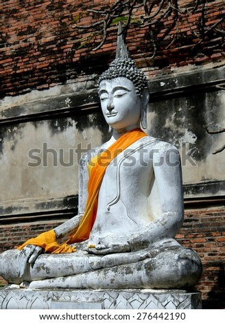 Ayutthaya, Thailand - December 28, 2005:  A large seated Buddha statue at the base of the great brick Chedi at Wat Yai Chai Mongkon