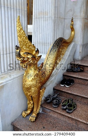 Bangkok, Thailand - December 26, 2011:  Sneakers and sandals sit on the steps next to a gilded naga dragon at Royal Wat Boworniwet\'s Ubosot sanctuary hall