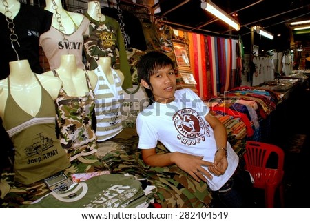 Bangkok, Thailand - December 17, 2006:  Thai teen aged youth selling clothing at his tented stall on Sukhamvit Road