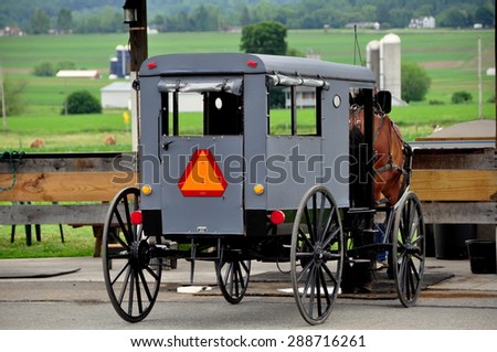 Ronks, Pennsylvania - June 4, 2015:  A traditional Amish buggy overlooking rolling pastures and an Amish farm
