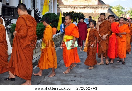Chiang Mai, Thailand - December 19, 2012:  Barefoot novitiate teenage monks wearing orange robes enter the ubosot sanctuary hall for morning prayer at Wat Chedi Luang