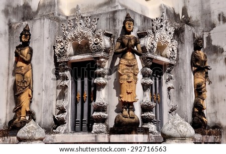 Chiang Mai, Thailand - December 25, 2012:  Statues of Thai Khong dancers decorate the base of an opulent white pagoda at Wat Nantaram  *