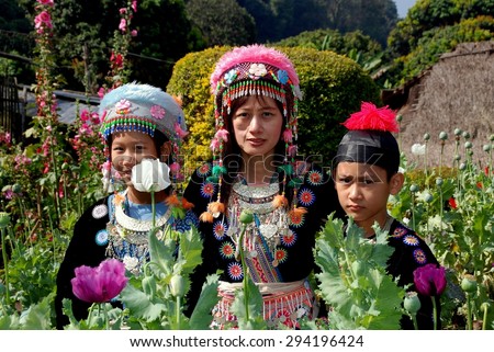 Doi Poi, Thailand - December 24, 2006:  Thai family wearing traditional hilltop village clothing visiting a garden of opium Poppies and Hollyhocks