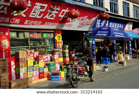 Pengzhou, China - April 5, 2013:  Chinese grocery store with Pepsi-Cola umbrellas and cartons of soft drinks piled outside