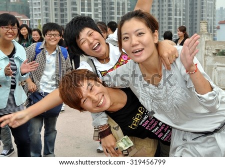 Mianyang, China - October 15, 2010:  A Group of university students ham it up on the approach bridge to the Sheng Shui Buddhist temple