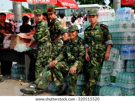 Pengzhou, China - May 15, 2008:  Chinese soldiers standing with donated bottled water for the victims of the 5-12-08 Sichuan Province earthquake