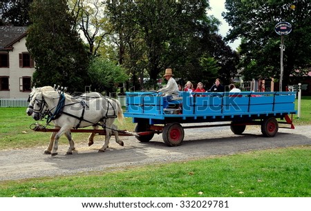 Lancaster, Pennsylvania - October 14, 2015:  Driver in high straw hat takes children for a wagon ride pulled by two white horses at the Landis Valley Village and Farm Museum