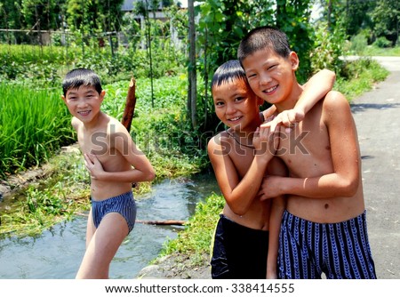 Jiu Chi Town, China - July 13, 2007:  Three young Chinese boys in their bathing suits at a small stream where they swim on a hot summer afternoon