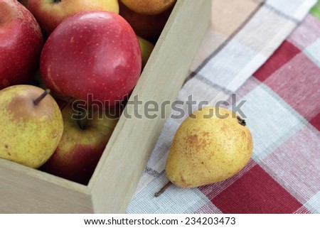 Pear next to a box full of apples and pears.
