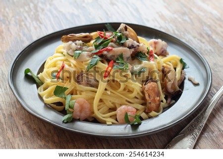 Fettuccine with seafood, chili and parsley on a tin plate.
