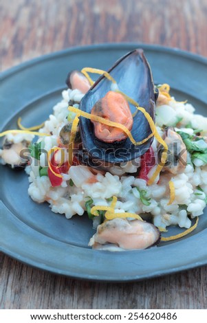 Risotto with seafood, chili and parsley on a tin plate.