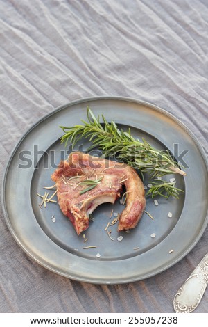 Shallow fried lamb cutlet with rosemary and sea salt on a grey tin plate.