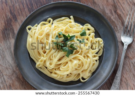 Fettuccine alfredo with butter, parmesan and parsley on a tin plate.