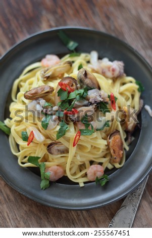 Fettuccine with seafood, chili and parsley on a tin plate.